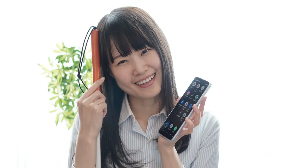 スマートフォンと白杖を手にする視覚障害のある女性